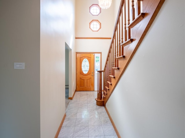 entryway featuring a towering ceiling, stairway, baseboards, and marble finish floor