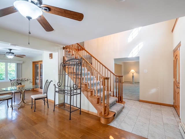 stairway featuring a baseboard radiator, ceiling fan, baseboards, and wood finished floors