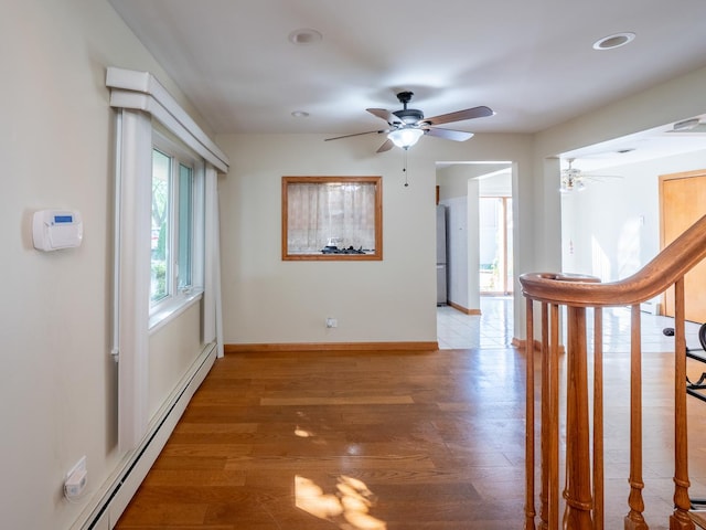 hallway featuring light wood-type flooring, baseboards, and baseboard heating