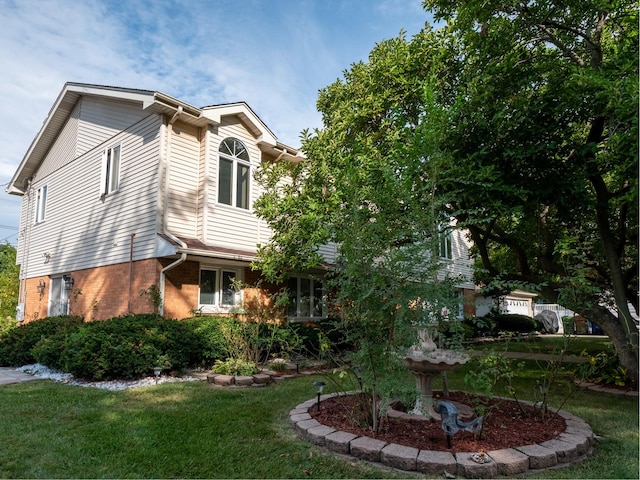 view of side of property featuring brick siding and a yard