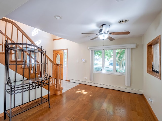 entryway with visible vents, a ceiling fan, wood finished floors, stairs, and a baseboard heating unit