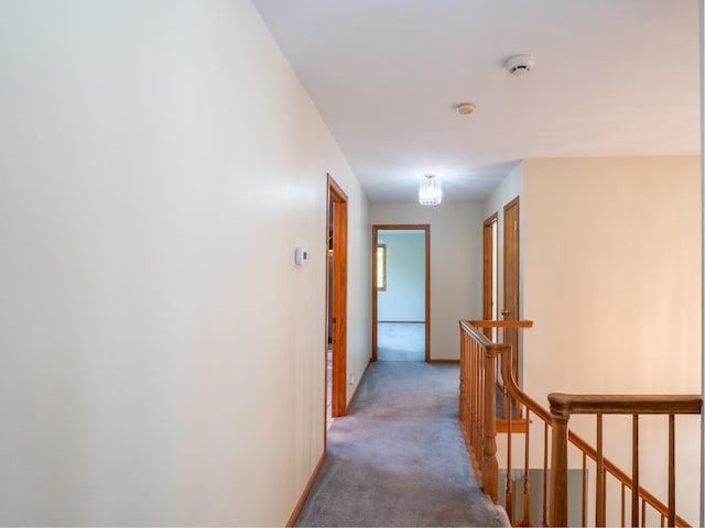 corridor with baseboards, light carpet, and an upstairs landing