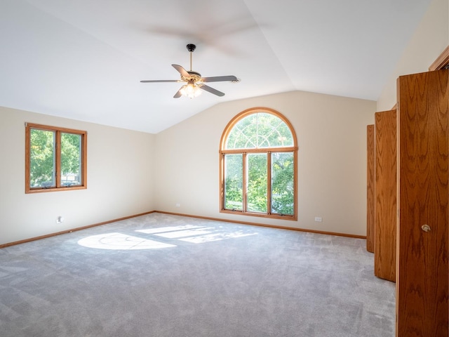 spare room featuring carpet, ceiling fan, lofted ceiling, and baseboards