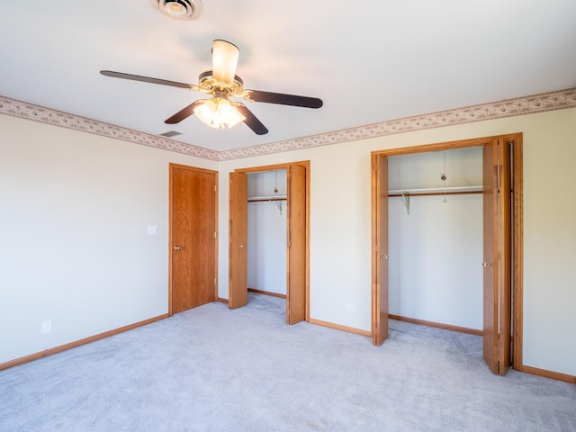 unfurnished bedroom featuring visible vents, baseboards, two closets, and light colored carpet