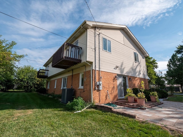 view of side of property with a patio area, brick siding, a lawn, and central AC unit