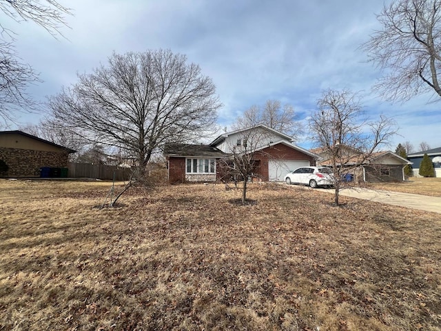 view of front facade featuring brick siding, an attached garage, a front yard, fence, and driveway