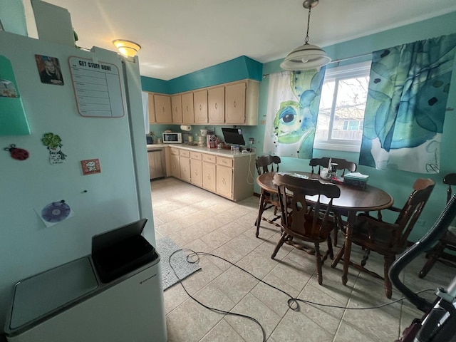 kitchen featuring white appliances, light countertops, decorative light fixtures, and light brown cabinetry