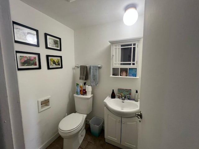 half bath with baseboards, vanity, toilet, and tile patterned floors