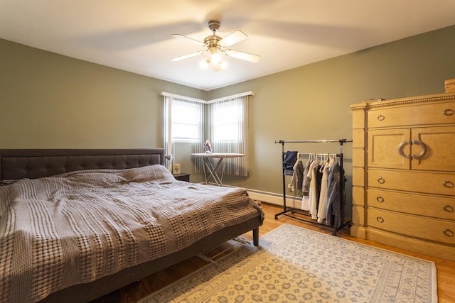 bedroom with a ceiling fan, light wood-style floors, and a baseboard radiator