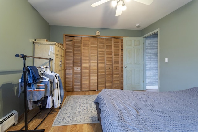 bedroom featuring a closet, wood finished floors, ceiling fan, and a baseboard radiator