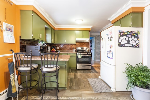 kitchen featuring stainless steel range with gas stovetop, green cabinets, freestanding refrigerator, and a peninsula