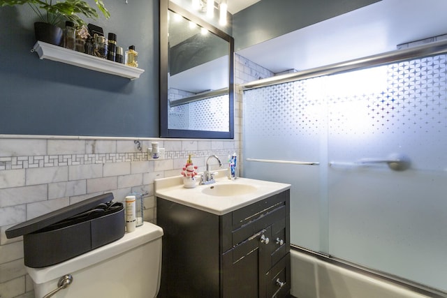 bathroom with vanity, tile walls, toilet, and enclosed tub / shower combo