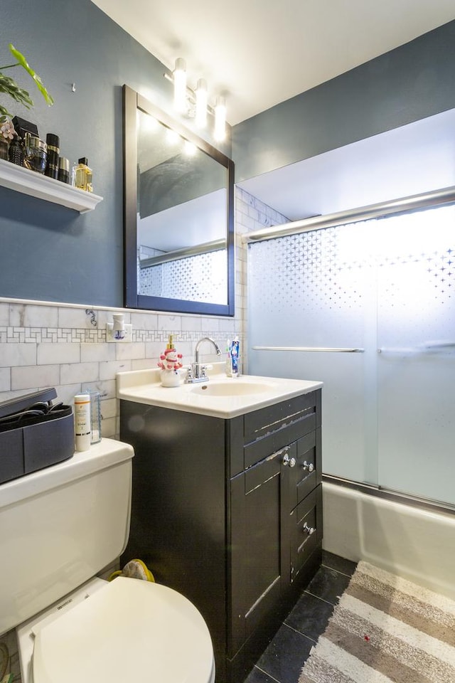 full bathroom featuring vanity, tile patterned flooring, tile walls, toilet, and combined bath / shower with glass door