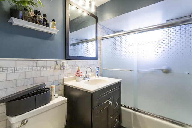 full bath with toilet, vanity, tile walls, and shower / bath combination with glass door