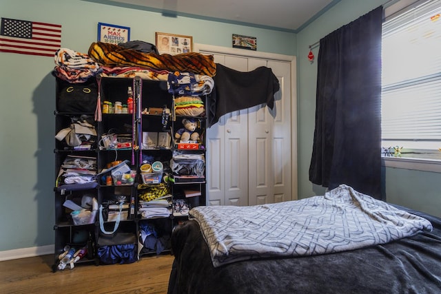 bedroom with a closet, crown molding, baseboards, and wood finished floors