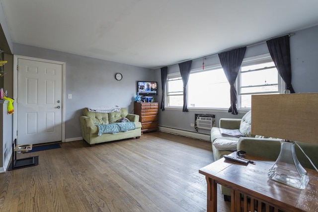 sitting room featuring a baseboard radiator, baseboards, a wall unit AC, and wood finished floors