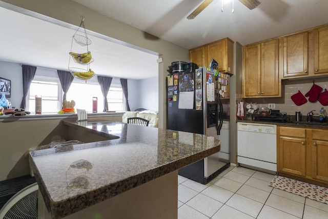 kitchen with a sink, stainless steel fridge, brown cabinetry, decorative backsplash, and dishwasher