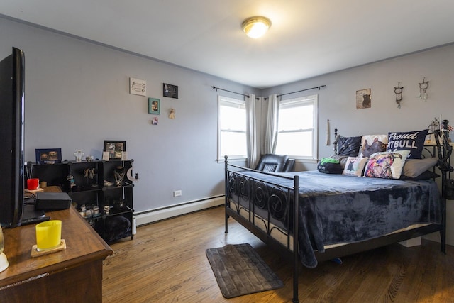 bedroom featuring wood finished floors, baseboards, and baseboard heating