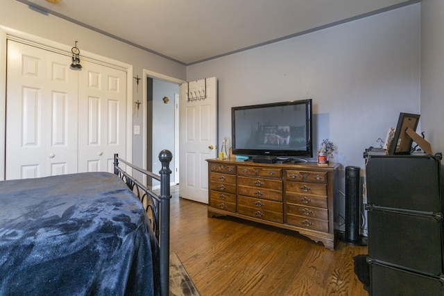 bedroom featuring a closet, freestanding refrigerator, and wood finished floors