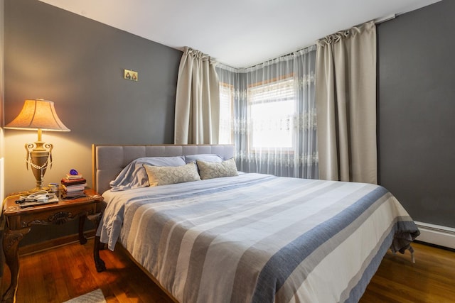 bedroom featuring a baseboard heating unit and wood finished floors