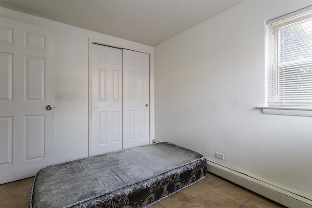 bedroom with a closet and baseboard heating