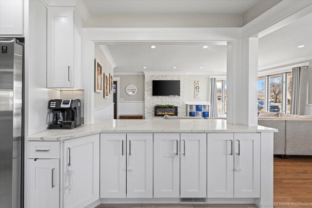 kitchen with open floor plan, white cabinetry, freestanding refrigerator, and visible vents