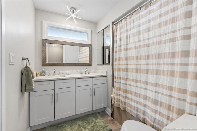 bathroom featuring double vanity, toilet, and a sink