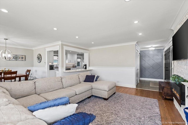 living room with an inviting chandelier, recessed lighting, wood finished floors, and ornamental molding