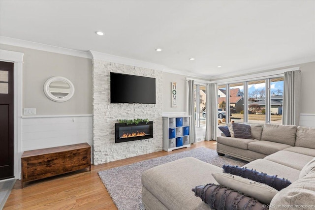 living room featuring wood finished floors, ornamental molding, a fireplace, and wainscoting