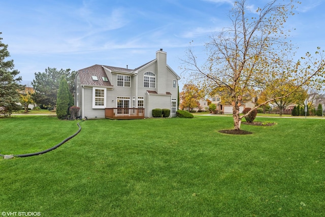 rear view of house with a lawn, a chimney, a deck, and roof with shingles