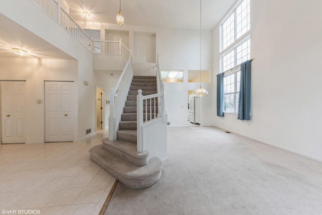 stairway featuring baseboards, a high ceiling, and carpet flooring