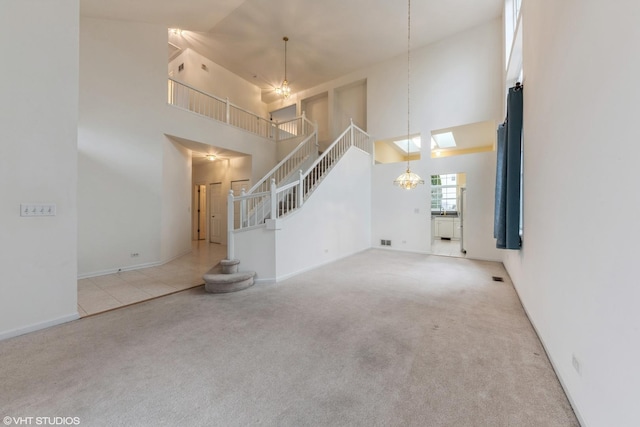 unfurnished living room featuring an inviting chandelier, stairway, carpet, and a high ceiling