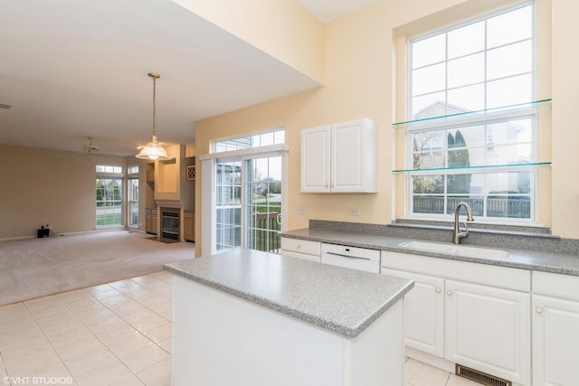 kitchen with visible vents, a sink, dishwasher, light colored carpet, and a center island