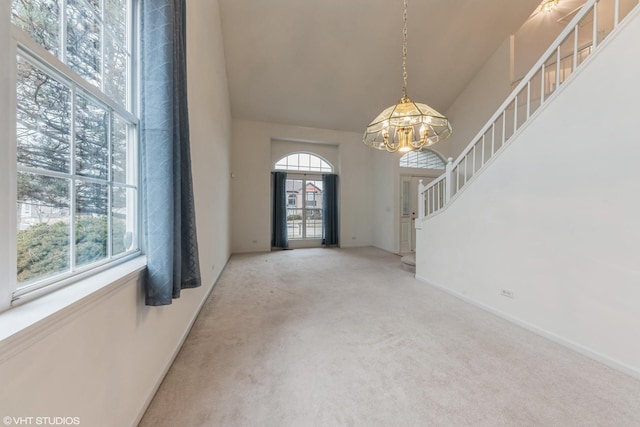 foyer entrance with carpet, a healthy amount of sunlight, a towering ceiling, and stairs