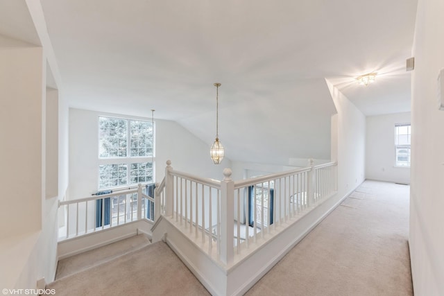 hall featuring vaulted ceiling, a notable chandelier, and carpet flooring