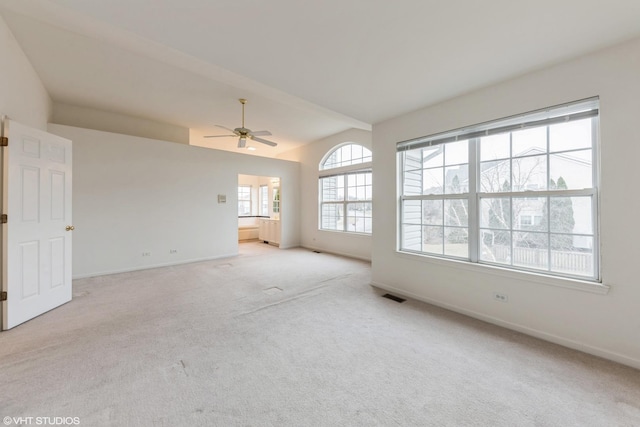 unfurnished living room featuring visible vents, baseboards, light colored carpet, ceiling fan, and vaulted ceiling