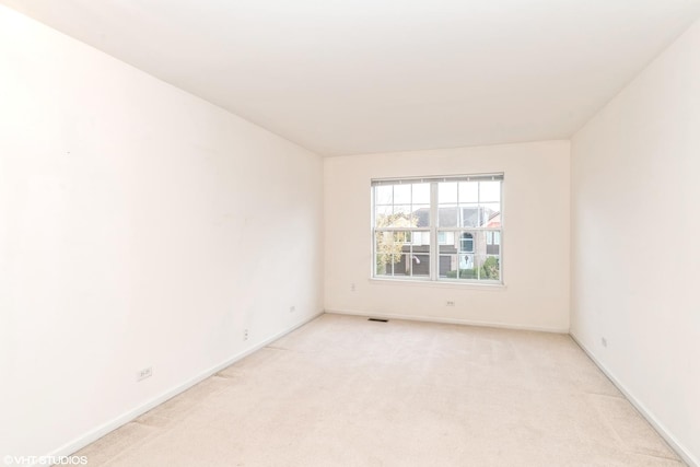 empty room featuring visible vents, baseboards, and light carpet