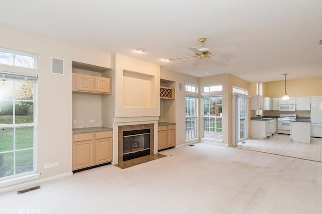 unfurnished living room featuring a wealth of natural light, visible vents, a sink, a fireplace, and light colored carpet