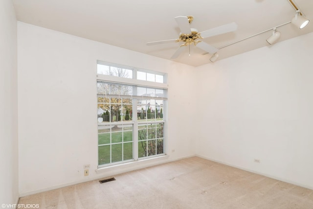 unfurnished room with a ceiling fan, visible vents, baseboards, track lighting, and carpet flooring