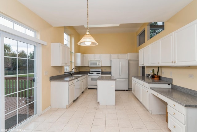 kitchen with a sink, white appliances, dark countertops, and a center island