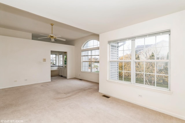 unfurnished room featuring a ceiling fan, baseboards, visible vents, radiator heating unit, and light carpet