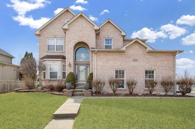 traditional-style home with brick siding, a front yard, and fence