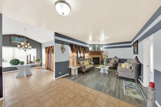 26800 Basswood Cir, Plainfield, IL 60585 - tiled living room with a tiled fireplace, lofted ceiling, baseboards, and a chandelier