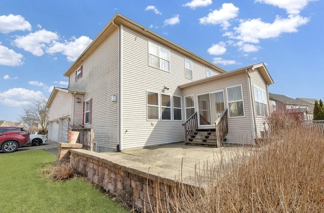 rear view of property featuring driveway, a sunroom, a garage, a patio area, and a lawn