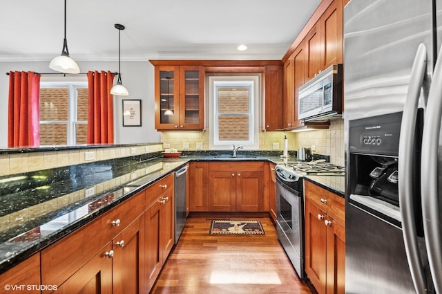 kitchen with a sink, decorative backsplash, appliances with stainless steel finishes, and dark stone countertops