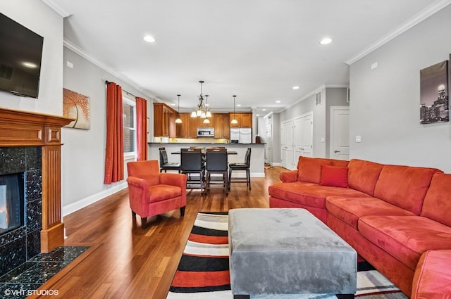 living room featuring baseboards, wood finished floors, a fireplace, and ornamental molding