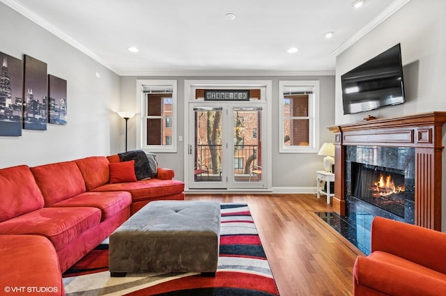 living room featuring wood finished floors, recessed lighting, crown molding, a premium fireplace, and baseboards