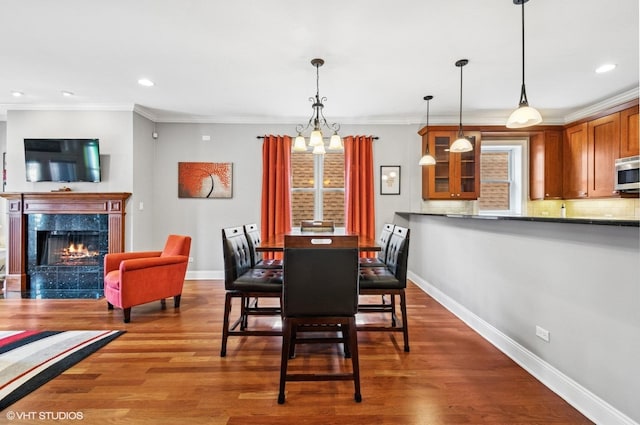 dining area with dark wood-style floors, a fireplace, baseboards, and ornamental molding