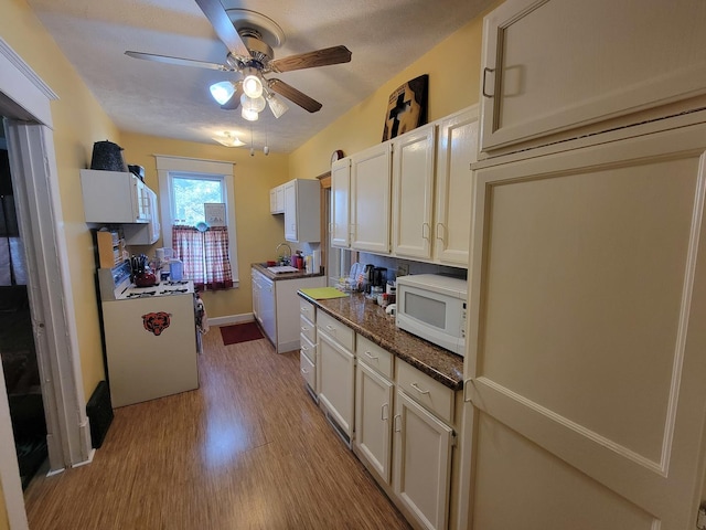 kitchen with range, white microwave, light wood-style flooring, ceiling fan, and a sink