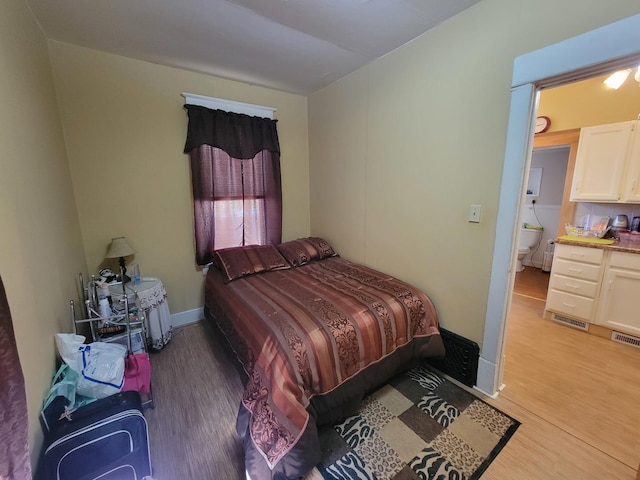 bedroom with baseboards, visible vents, and light wood finished floors